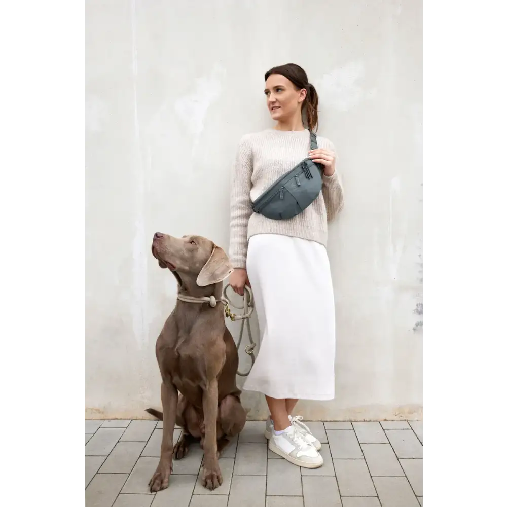 Frau mit beige Pullover und weißem Rock, Teal Bum Bag Emma, neben Hund