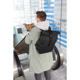 Mann mit Rolltop Rucksack Yoska und Hund auf Rolltreppe unterwegs